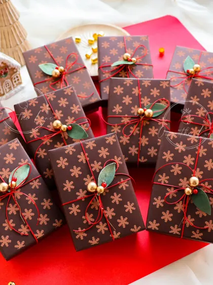 The beautiful snowflake-themed wrapping I use for my Christmas orders, finished with a red string and gold holly berries.