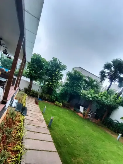A long view of a residential backyard we landscaped. The healthy green lawn is bordered by a stone path and a variety of trees and shrubs.