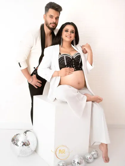 A full-length portrait from the black-and-white themed maternity shoot, showcasing the complete look and the stylish studio setup.