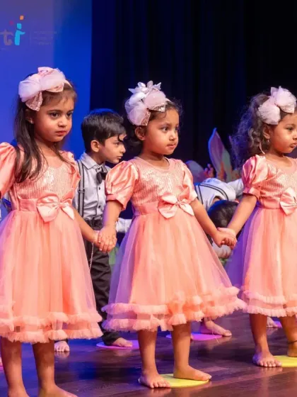 Young performers in beautiful peach dresses hold hands on stage. The sense of unity and friendship among the children is heartwarming to see.