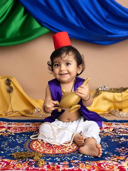 Holding his magic lamp, this little boy's smile is pure magic. The colorful draping in the background adds to the Arabian nights feel.
