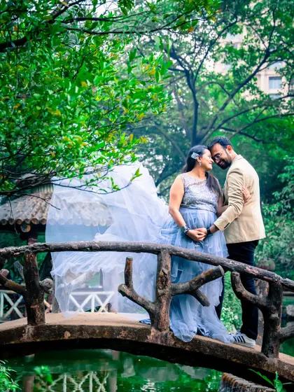 The flowing gown creates a sense of movement and romance in this shot on a bridge. The misty, natural background adds to the dreamy and ethereal quality of the photograph.