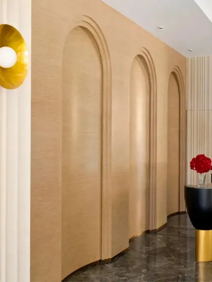 I love playing with architectural shapes to guide the eye and create flow. In this hallway, a series of curved, arched doorways adds a soft, organic feel, contrasting with the sleek marble floor. A simple, elegant brass wall sconce provides warm, ambient light.