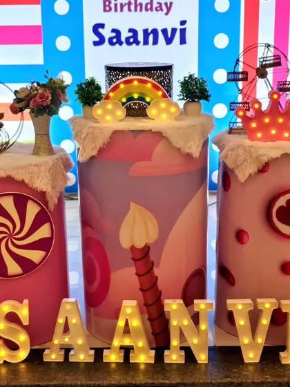A close-up of the themed pedestals at Saanvi's party, decorated with candy and rainbow motifs.