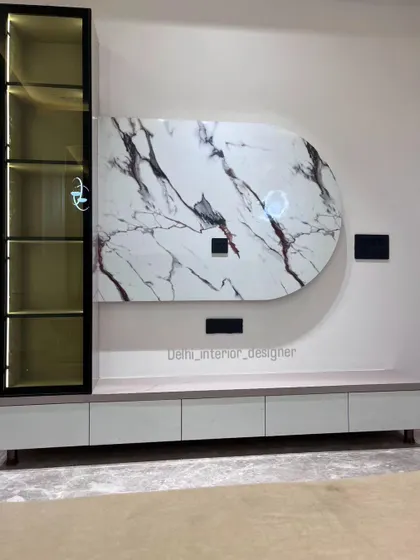 A modern bedroom TV unit. The design features an abstract marble-finish panel, a sleek console, and an illuminated glass display cabinet, combining storage and style.