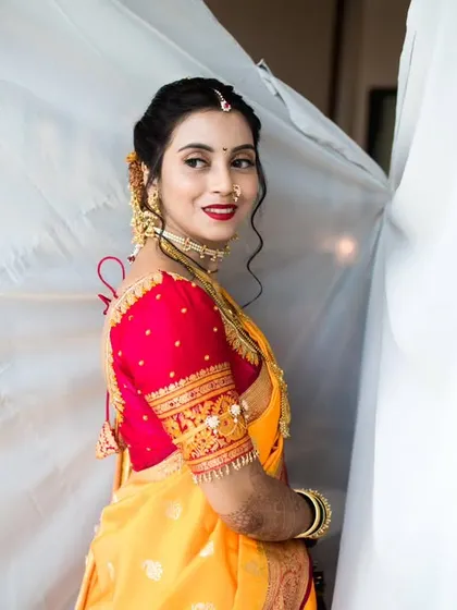 A beautiful profile shot of the bride looking away with a gentle smile, highlighting her makeup and the details of her embroidered blouse.
