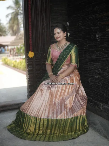 A seated pose in the peach and green silk Langa Voni, showing the flow and volume of the skirt.