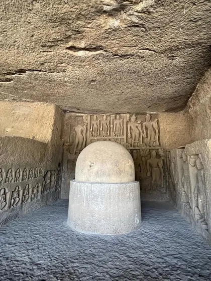A view of a stupa inside a cave hall, showing the surrounding carved figures along the walls.