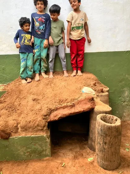 Four boys stand proudly atop the cobb house they built from logs and mud. This collaborative construction project passed the "4 atop" test, a testament to their engineering skills and teamwork.