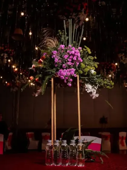 An elegant table centerpiece with purple flowers and tall, slender stands, set for a glamorous Sangeet dinner.