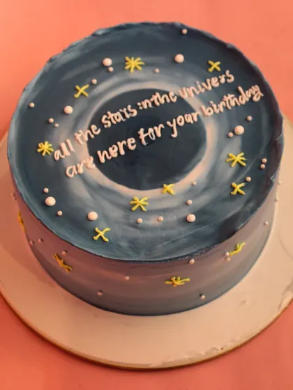 A top-down view of the galaxy cake, showing the swirling universe design and the message "All the stars in the universe are here for your birthday."