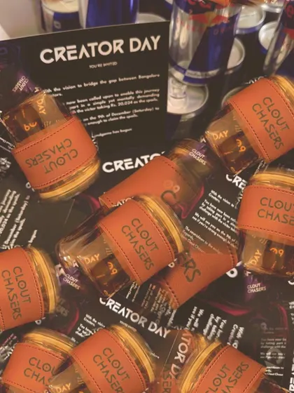 An artistic shot of the 'Clout Chasers' branded tumblers scattered amongst event cards, highlighting the cool, modern aesthetic we can achieve for your brand.