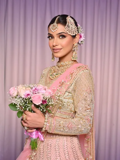 The full look, showcasing the pastel lehenga and the elegant floral bun.