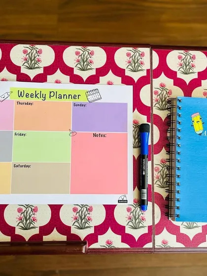 The reusable weekly planner shown on a desk next to one of my notebooks, a perfect organizational combo.
