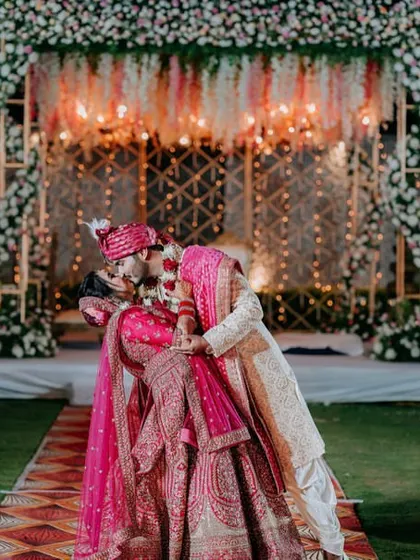 A romantic kiss seals the deal at the mandap. A beautiful moment captured against the backdrop of suspended florals and warm lights.