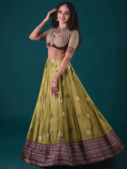 A dynamic shot of the model in the olive green Banarasi lehenga, showing the beautiful movement of the skirt and the intricate details of the blouse.