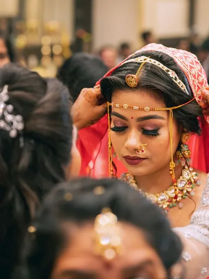 A behind-the-scenes moment as the bride gets ready, with her matha patti being adjusted.