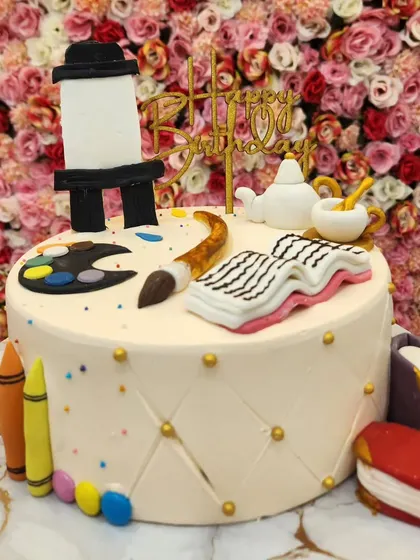 An artist-themed cake, perfect for someone who loves to paint and read. It features a fondant easel, paintbrush, palette, and books.