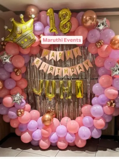 A sweet 18th birthday party with a circular balloon arch in pink and purple. A large crown balloon and foil letter balloons for the name add a special touch.