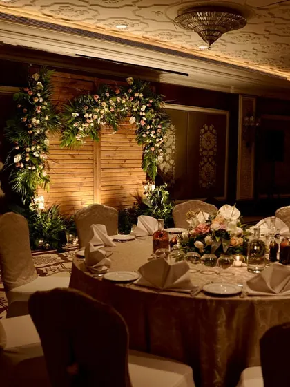 A view of the intimate dinner setup, with a beautiful floral arch in the background. The round tables are elegantly dressed, and the warm lighting creates a welcoming and sophisticated atmosphere.