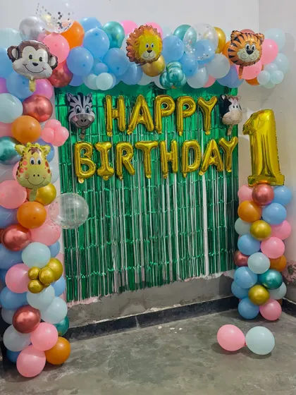 A colorful jungle-themed first birthday arch. I used a green tinsel backdrop and lots of friendly animal foil balloons like a monkey, lion, and giraffe.