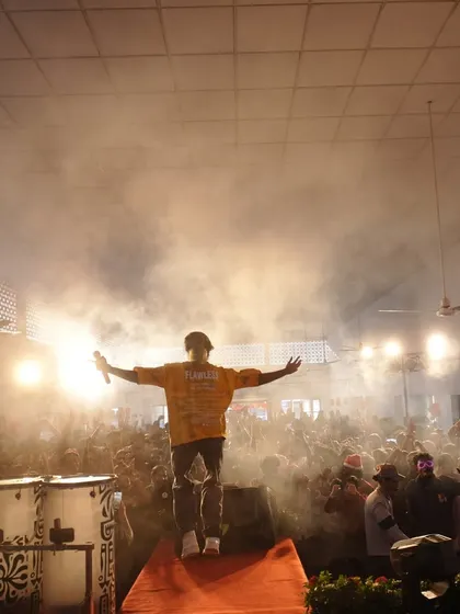A powerful silhouette shot of me on stage, arms outstretched in front of a massive crowd, with smoke and bright lights creating a dramatic effect.