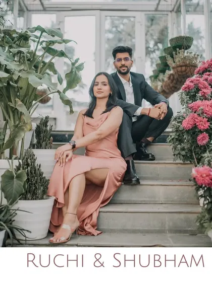 A stylish couple poses on the steps of a greenhouse, surrounded by vibrant flowers. This shot showcases a modern and elegant pre-wedding style in a beautiful hill station setting.