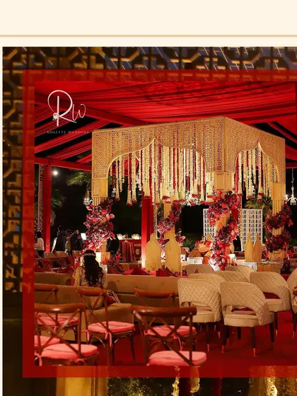 A wider view of the wedding setup, showing the mandap and guest seating. The entire space is unified by the red and gold color palette.