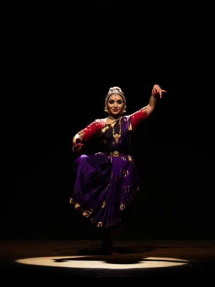 Meera Krishna under a single spotlight, creating a dramatic and intimate atmosphere for her solo performance.
