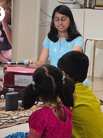 A group of children listening intently as their teacher plays the harmonium. This is where active listening skills and a deep appreciation for Raag Sangeet begin to develop.