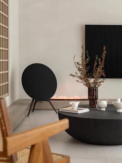 A minimalist living room detail, featuring a modern woven-back wooden chair and a low, round coffee table, creating a serene and uncluttered aesthetic.