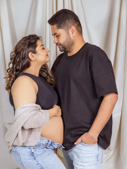 A casual and modern maternity look. The couple, dressed in jeans and t-shirts, shares an intimate gaze, showing that beautiful portraits can be created with a relaxed and comfortable style.