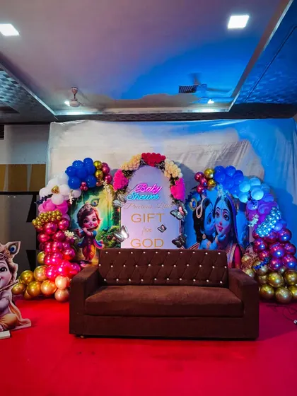 The same premium baby shower setup shown with a sofa for guest seating and photos. The lighting enhances the vibrant colors of the decor.