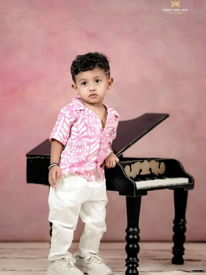 A little musician standing by his piano. The pink backdrop with musical notes is perfect for a rockstar-themed shoot.