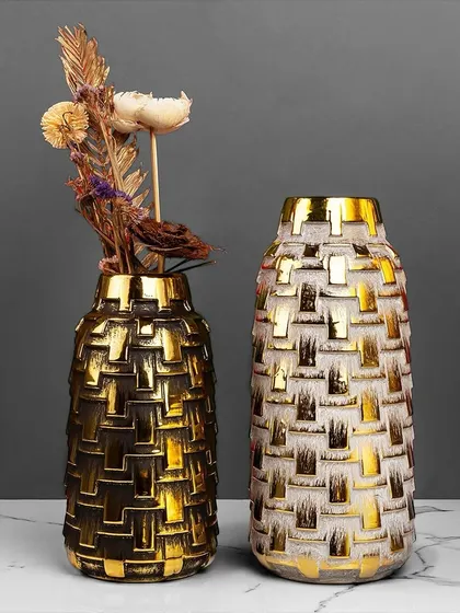 This pair of decorative vases features a textured, woven-like pattern in black and white with a gold finish. They are perfect for holding dried flowers or standing alone as modern sculptural pieces.