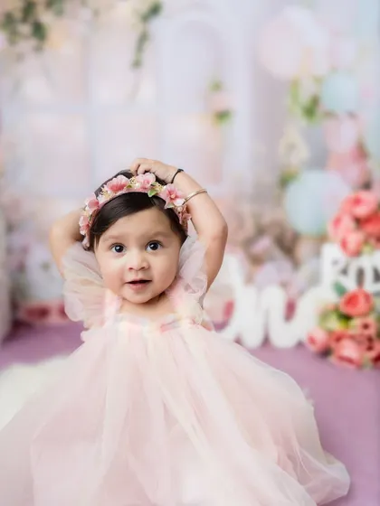 A beautiful one-year-old princess in a pink dress, surrounded by a dreamy floral setup.