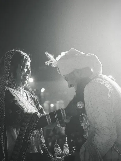 A dramatic black and white photo of a wedding ritual, with strong backlighting creating a timeless and artistic feel.