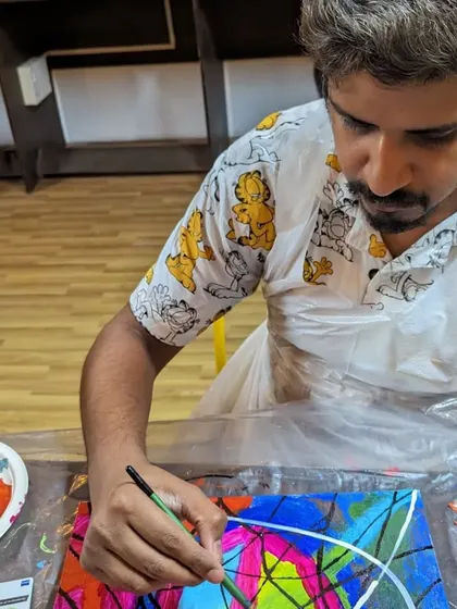 A participant adding fine lines to his geometric abstract painting, creating a sense of order and structure within the vibrant colors.