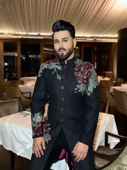 A front-facing view of the black floral embroidered sherwani, highlighting the asymmetrical design of the embroidery.