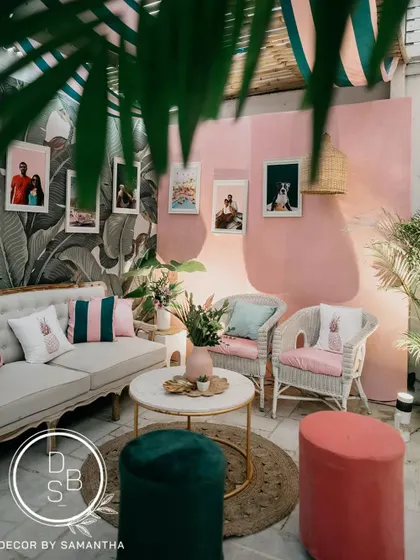 This cozy corner of the brunch setup features a pink textured wall, wicker chairs, and personal photos of the couple, making the space feel intimate and story-driven.