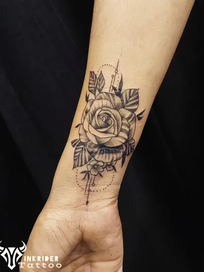This black and grey rose tattoo was designed to cover a scar on the wrist. The layered petals and leaves, combined with geometric line work, effectively hide the scar tissue beneath a beautiful floral design.