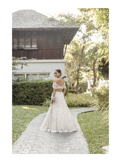 The bride looking back, showcasing the beautiful design of her wedding lehenga.