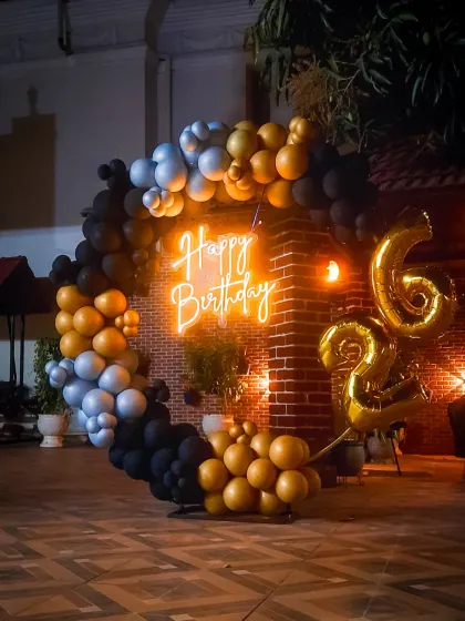This outdoor birthday decoration shows how I can create a stylish party atmosphere in any setting. The modern balloon arrangement in black, gold, and silver, combined with a neon sign against a brick wall, gives a cool, urban vibe to the celebration.