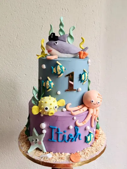 Dive into this fun underwater-themed cake for a first birthday. It features a friendly shark, a pufferfish, and an octopus, all swimming in a colorful two-toned ocean.