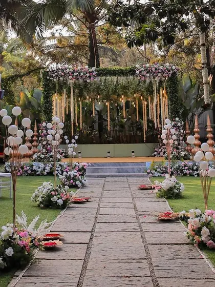 A wide shot of an elaborate wedding setup on our main lawn. The hanging floral arrangements and decorated aisle create a grand and luxurious feel.