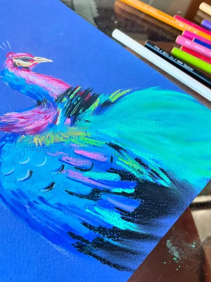 As I build the layers, the peacock's form begins to take shape. I use different shades of blue and green pastels to create the texture of the feathers.