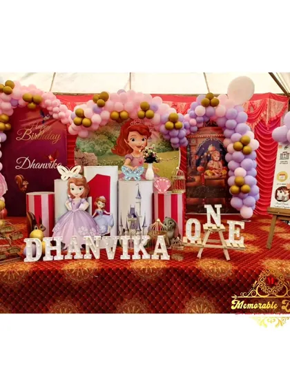 A grand Sofia the First themed stage decoration for a first birthday, complete with a castle prop and personalized name sign.