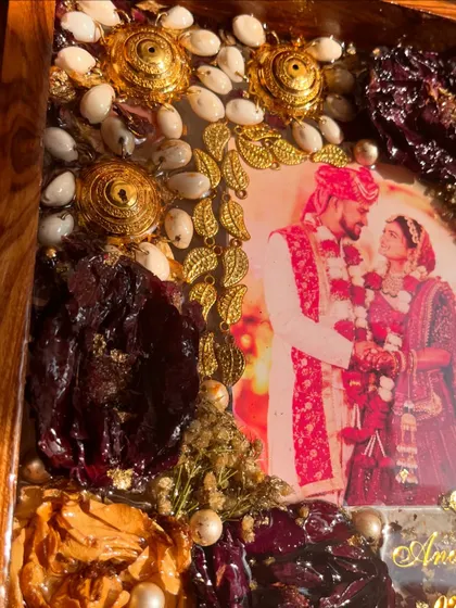 A close-up of a teakwood frame showing the intricate details of preserved kaleera and varmala flowers. The combination of textures and colors is simply stunning.