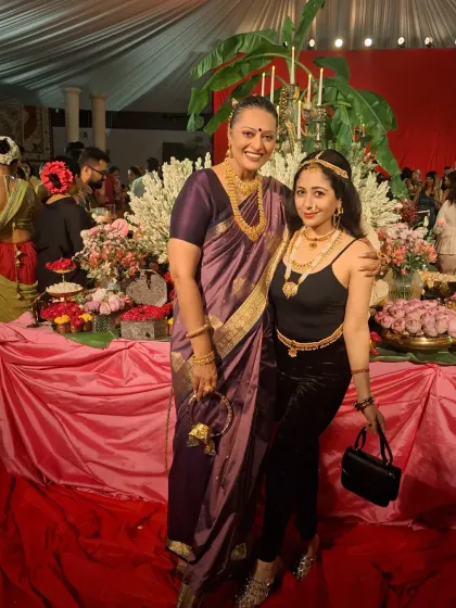 At the 'Art of Adornment' event, surrounded by beautiful floral decor. My classic purple Kanjivaram silk saree was chosen to honor the theme of timeless Indian elegance.