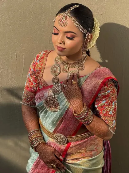 Bride Anusha in a moment of reflection. The intricate embroidery on her blouse sleeves is visible, showcasing the 360-degree craftsmanship.